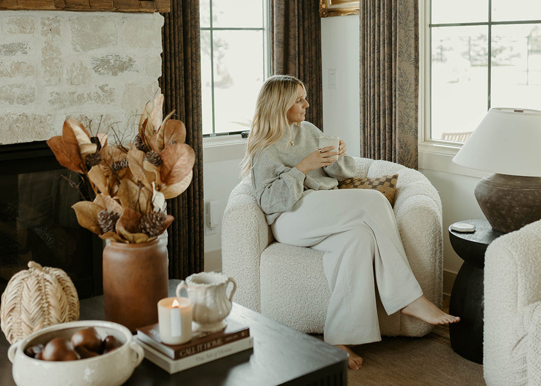 Woman sitting in a cozy living room with decorative elements.